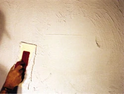 A plaster overcoat renews the wall’s stucco-like appearance. Once dry, brush away any loose plaster, then prime and paint the surface.