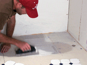 After planning your layout, spread tile adhesive onto the cement board with a notched trowel.