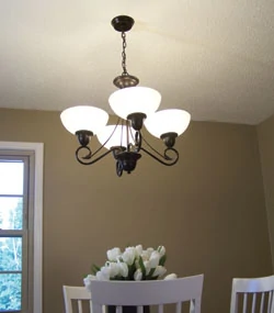 The fixture shown is a four-light chandelier Progress Lighting, featuring an antique bronze finish and etched watermark glass.