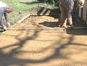 A screed board is used to level the concrete to the form boards.
