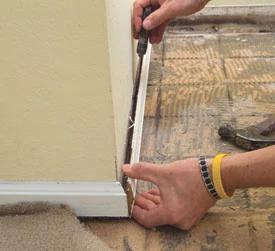 A stiff blade putty knife is a good tool for getting behind baseboards for removal.
