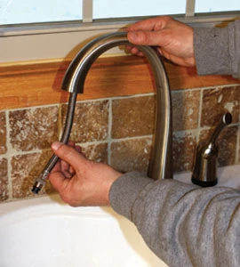 Feed the pull-down hose assembly through the spout and out the bottom of the shank beneath the sink.