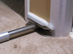 Position the foot of a carpet stretcher against solid wall framing.