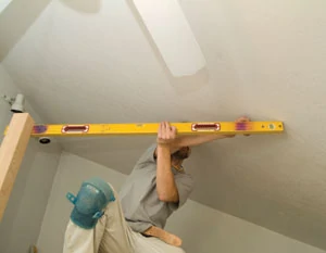 Use a level to transfer the top-of-guardrail mark on the newel post over to the point where the level section of the guardrail intersects the rake of the ceiling.