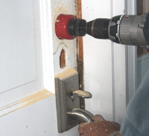 A hole-saw was necessary to cut a new hole for the deadbolt assembly.