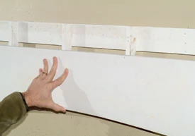 Install the frieze board over the furring strips at the desired elevation. Check the frieze board for level. Nail the frieze board into the furring strips.