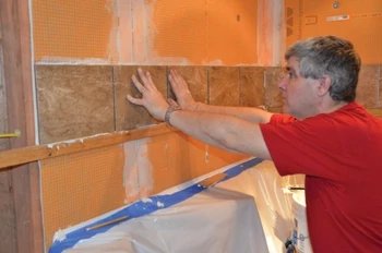 Hal fastened a ledger board above the bathtub, which kept the tile installation level while supporting the vertical load as the mortar set.