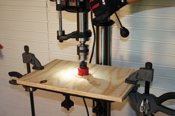 To build the auxiliary drum sanding table, first cut a piece of plywood to the exact dimensions of the drill press table. The, align the plywood's edges with the work table, clamp in place and bore a hole slightly larger than your sanding drum through the plywood.