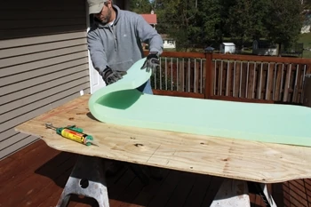 Use a sharp utility knife to cut the polyester foam to the same size and shape as the frame. Glue the foam to the plywood with polyurethane construction adhesive.