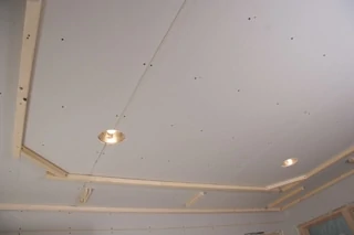 2x4 Lumber was ripped to form 1-1/2” strips for the framework of the tray ceiling. The strips are glued and screwed to chalk lines around the perimeter of the room. This photo is of a new construction job, but the same method can be followed for any existing ceiling.