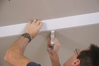 The edge of the bead that attaches to the lower ceiling is stapled in place along the chalk line. This edge will be concealed with joint compound later.