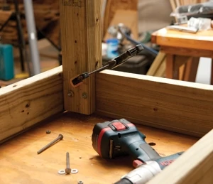Tap two bolts through the legs, tighten one, and then remove the clamp to drill the third hole.