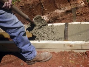 Fill the forms with concrete and level the top with a screed board.