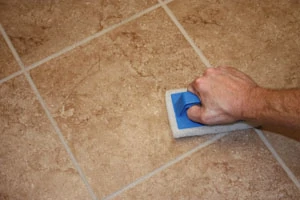 As you apply the grout, use a scrub pad, sponge and clean bucket of water to remove excess grout as you go.