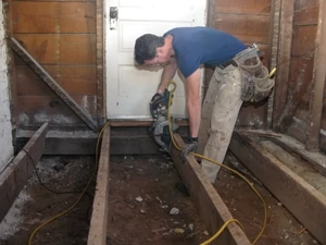 I cut away the old floor joists for replacement. Behind me you can see the sill plate literally rotting from the bottom up where it had been repeatedly soaked. The presence of a door means that layout needs to be spot-on, from framing to finished floor height.
