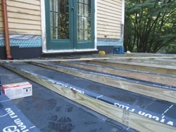 After new sheathing was installed, the roof was covered with a single sheet of EDPM rubber roofing. Then, Tapered 2x joists were installed to accommodate the slope of the roof. 