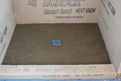 To create a shower floor from scratch, I use what is commonly called “dry pack mortar” or “deck mud’, which contains three ingredients; Portland cement, sand and water. The mortar bed is pitched toward the drain. 