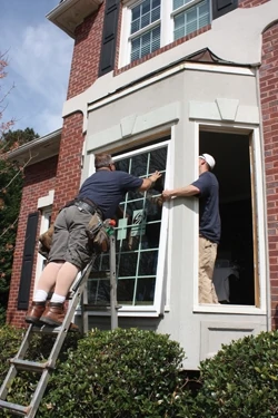Large units require some assistance when installing. A worker on the inside lifts the window with a suction cup. 