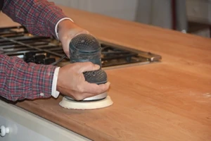 Start prepping the main counter wood surface with 80-grit to remove some of the stains that seeped into the wood. Work your way up to 220- grit sand paper. 