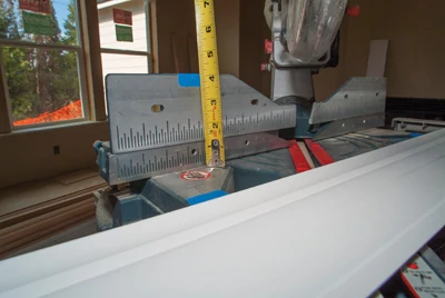 Use masking tape to mark the edges of the crown on the miter saw’s table and fence so it is positioned at the correct angle to the saw blade. 