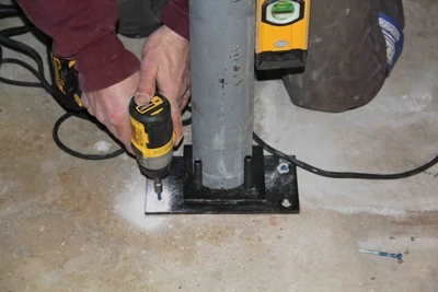 The bearing plate is fastened to the floor with concrete screws.