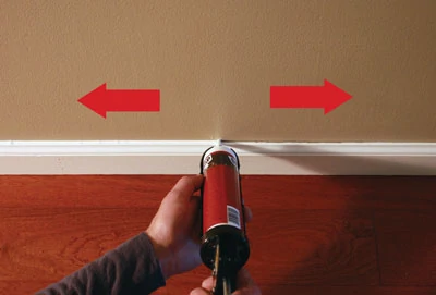 Hold the caulk gun at a 90-degree angle to strike a balance between pushing and pulling, and for easy visibility on both sides of the nozzle.