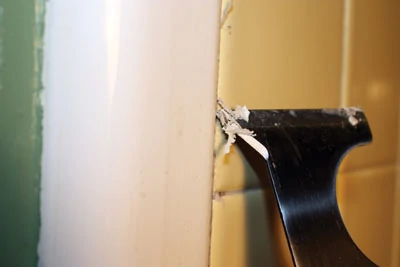 To remove old silicone caulk, cut the bead along each side with a utility knife and pull it from the joint. Carefully remove what remains with a paint scraper held at a shallow angle.