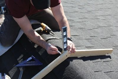 Use two pieces of wood to make a hinged angle finder. Use the angle finder on the roof ridge to determine the pitch.
