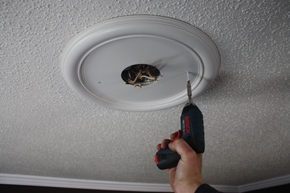 To hide some ceiling damage around the fixture box, I installed a decorative ceiling medallion with a couple of trim-head screws driven into the ceiling joist. The medallion is an accessory trim piece available at most home centers that sell fans. 