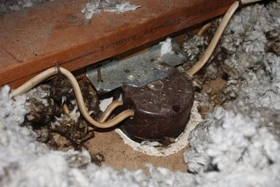 Inside the attic I found the old outlet box buried beneath loose insulation attached to the side of a ceiling joist. 