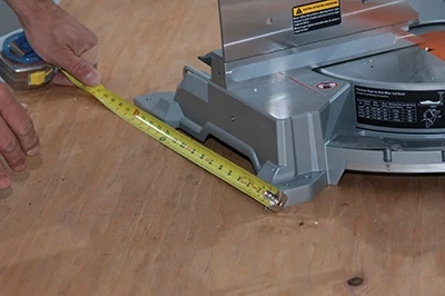 Measure the base of the miter saw to determine the width of the saw table. 