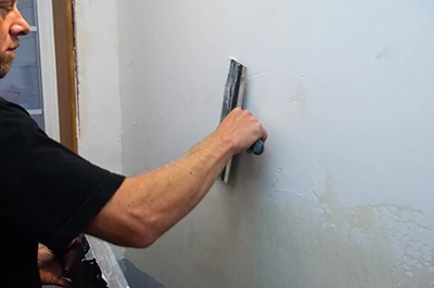 Monroe used a taping knife to apply a thin layer of joint compound on the wall.