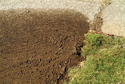 When I looked out and saw a geyser at the corner of the lawn, I shut the sprinkler zone off and saw that the water had deposited a fair amount of dirt and rocks on the sidewalk. This meant the problem was deep enough below the sod to blast out some substance. 