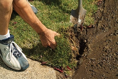 The initial goal in digging up the pipe is to fold back the sod without damaging the roots of the grass. 