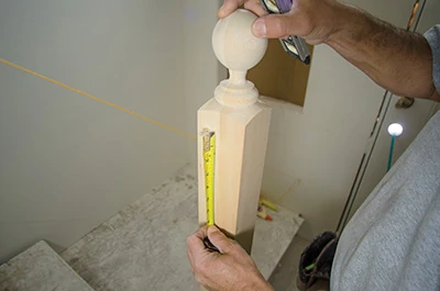 We measured from the mark on the newel post up to the desired intersection point (where we wanted the handrail to terminate), which indicated how much to cut off the base of the newel post. 