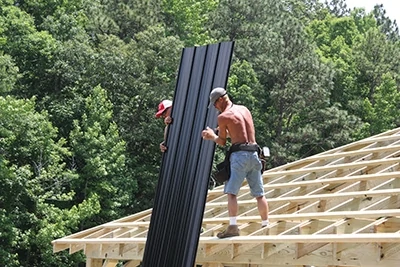 On this construction crew, one man delivers the panels to the two installers on the roof. 