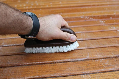 Use a soft-bristle brush to scrub in the direction of the grain. 