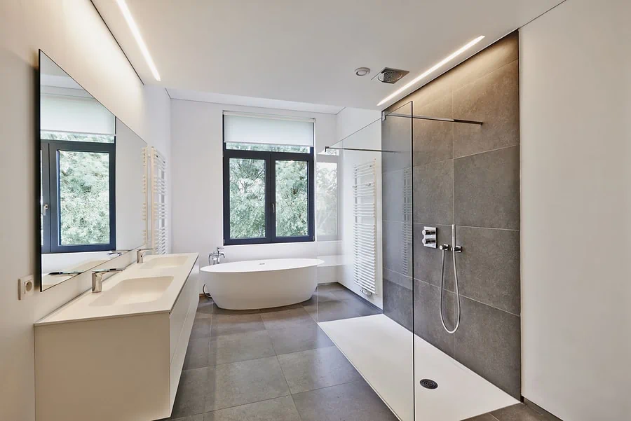 Bathtub in corian Faucet and shower in tiled bathroom with windows towards garden