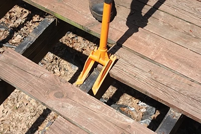 The Guster bridges over joists to pry up the decking with its forked demolition head.