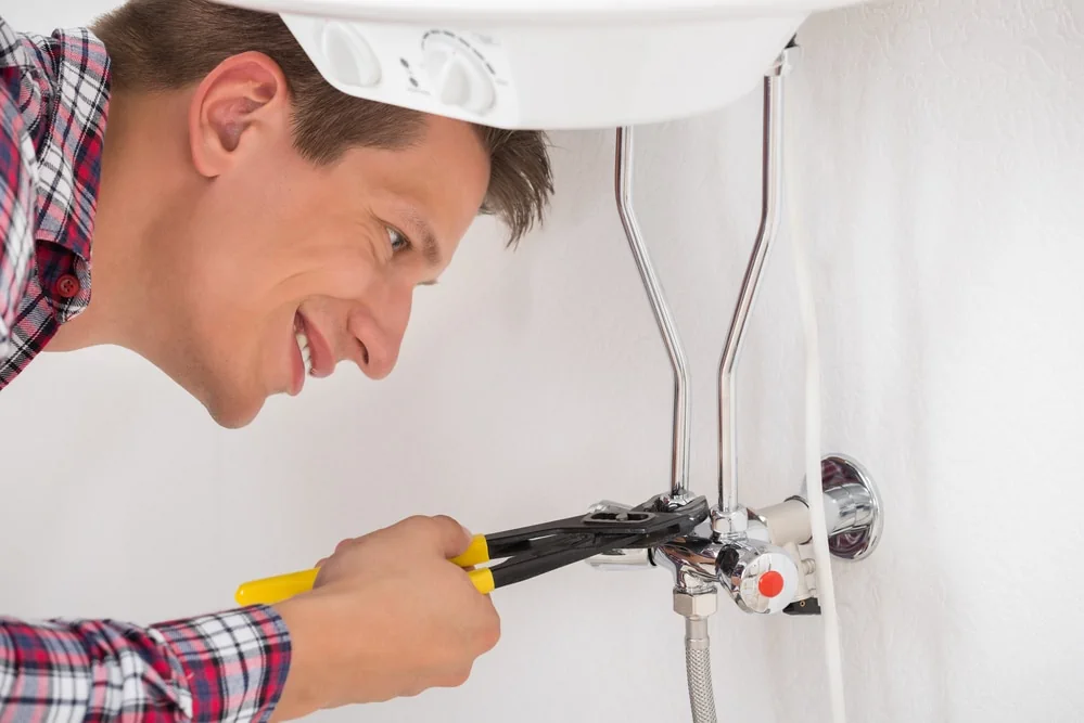 Happy Young Male Worker Repairing Electric Boiler With Wrench