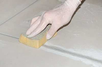 Use a damp sponge to clean excess grout as you apply it. Be prepared to repeat this procedure the day after installation. A sponge with an abrasive pad helps to scrub off dried grout sand and residue. Picture © thodonal/123RF