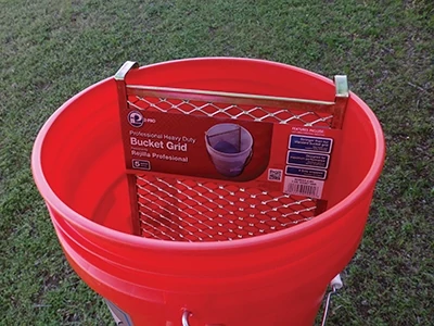 Using a paint grid inside a 5-gallon bucket proved to be the most efficient way to reload he roller when painting the roof. 