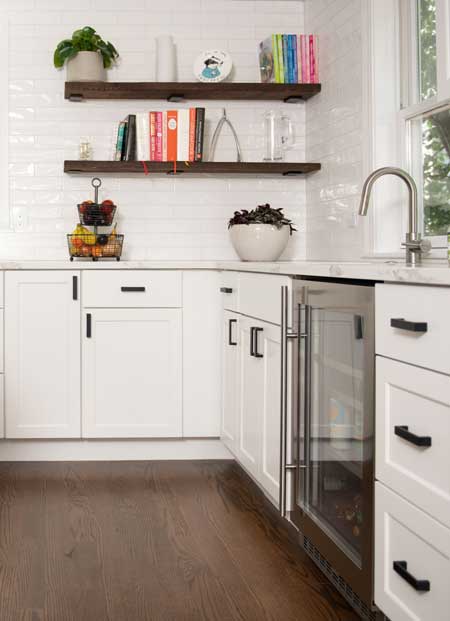 floating wooden shelves in white kitchen with stock cabinets and built in custom wine cooler