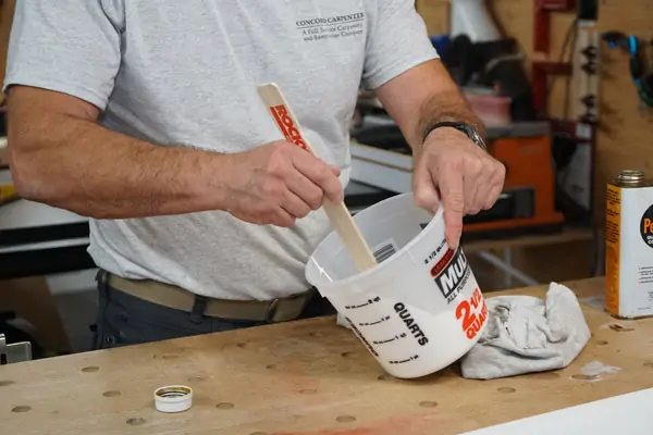 man mixing in paint conditioner to paint to help eliminate brush strokes and streaks
