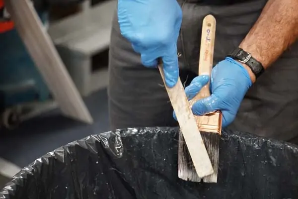 man cleaning oil paint brush with wire brush