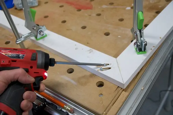 drilling screws into the pocket holes of a mitered frame