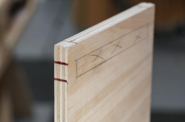 piece of oak with red marks lined up to the dado location marks on the wood