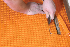 Schluter DITRA is rolled in place and cut to fit with scissors or a sharp knife.