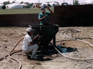 A portable concrete mixer, a concrete pump, a shotcrete gun, and hoses all being demonstrated in use